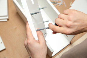 Assembling of furniture, closeup of tool in hand. Mounting screw